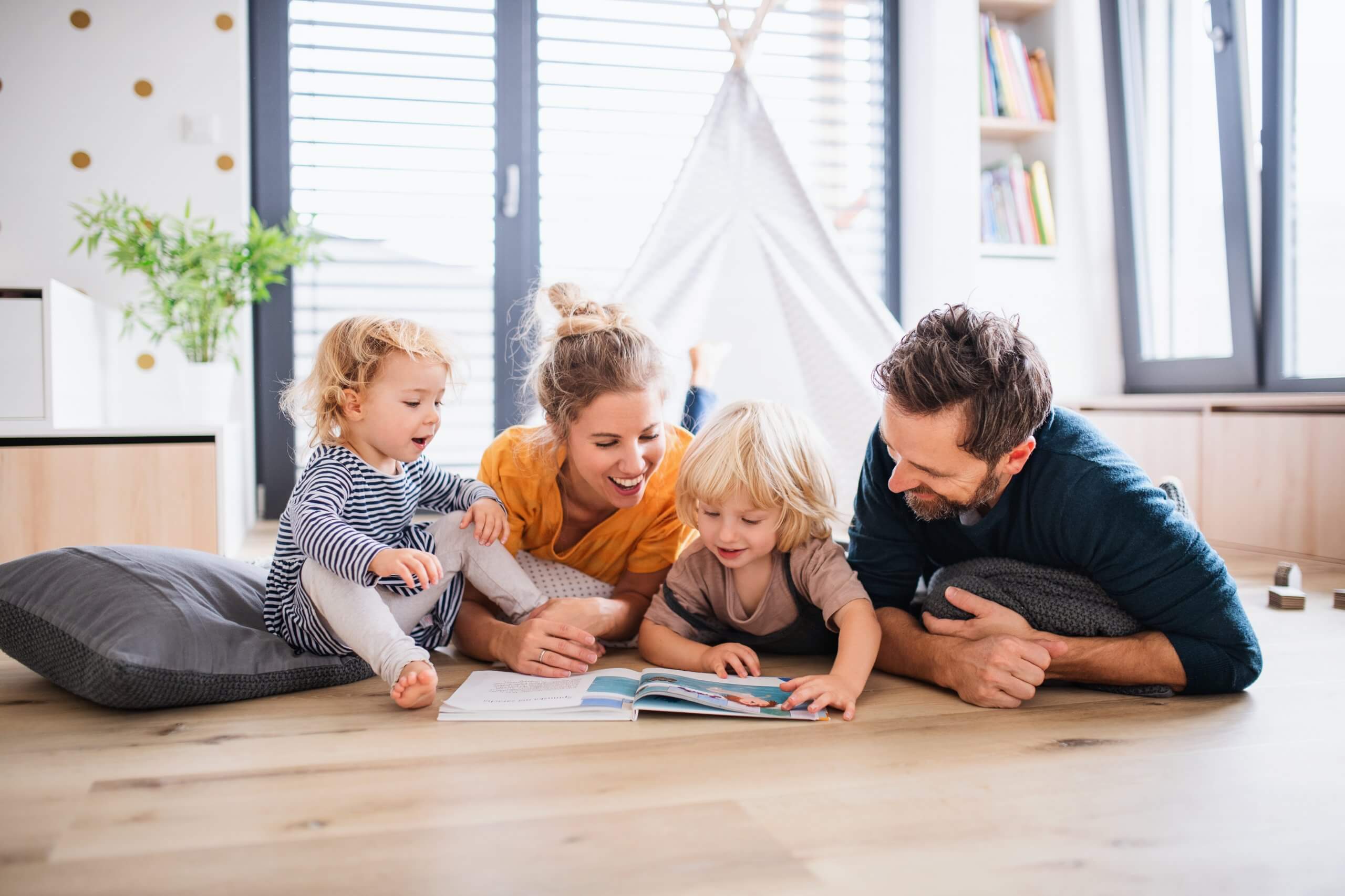 Young Family With Two Small Children Indoors In Bedroom Reading